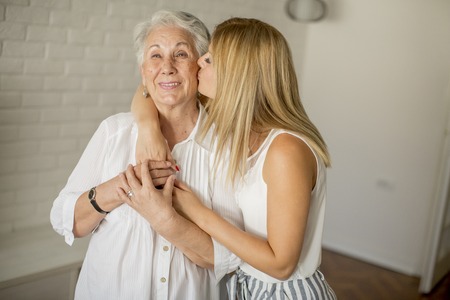 Granddaughter kissing grandmother in the room  at homeの写真素材