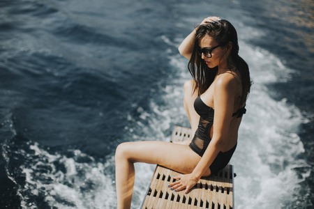 Pretty young woman relaxing on the yacht on sea at sunny dayの写真素材