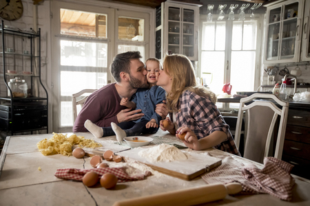Happy family making pasta in the kitchen at homeの写真素材