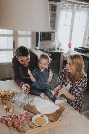 Happy family making pasta in the kitchen at homeの写真素材