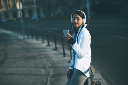 Pretty young woman takes a break after running in urban area