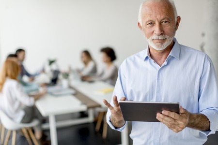 Portrait of senior businessman standing with digital tablet in his handの写真素材