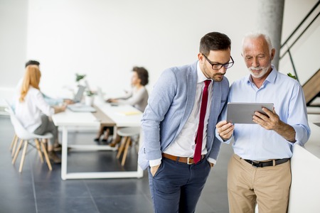 Portrait of businessmen with digital tablet in officeの写真素材