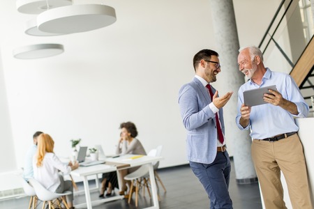 Portrait of businessmen with digital tablet in officeの写真素材