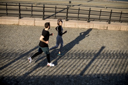 Healthy young couple running in the city with cityscape backgroundの写真素材
