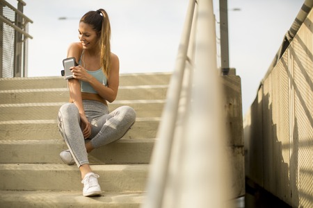 Portrait of pretty young female runner resting on the stairsの写真素材