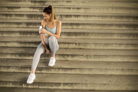 Portrait of pretty young female runner resting on stairs