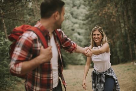 Hiker man holding womans hand and leading her on nature outdoorの写真素材