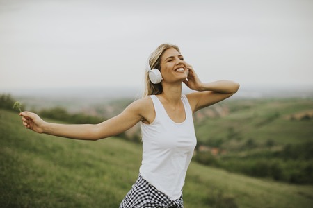 Happy young woman in nature listening to music on headphonesの写真素材