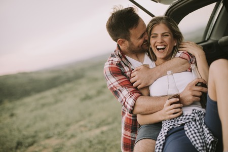 Loving couple sitting in the car trank during trip in the nature