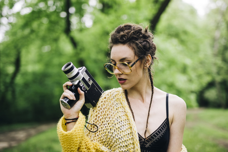 Portrait of young woman using an vintage cinema camera in a parkの写真素材