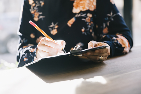 Woman hand writing in agenda on a desk at home or officeの写真素材
