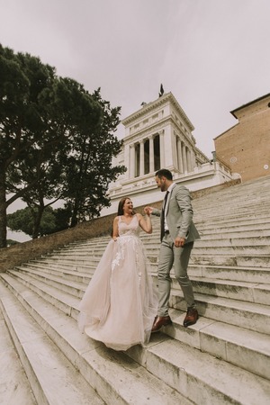 Loving bride and groom walking outdoors at Spagna Square and Trinita' dei Monti in Rome, Italy