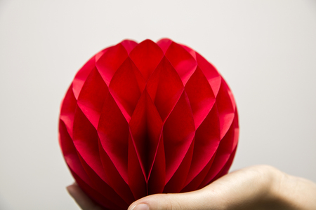 Red honeycomb pom-pom paper ball decoration on the human handの写真素材