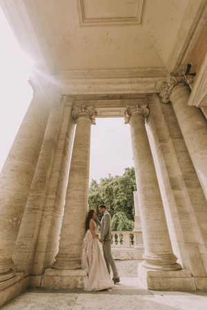 Young attractive newly married couple walking and posing in Rome with beautiful and ancient architecture on the background on their wedding dayのeditorial素材