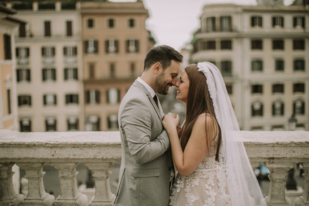 Young attractive newly married couple walking and posing in Rome with beautiful and ancient architecture on the background on their wedding dayの写真素材