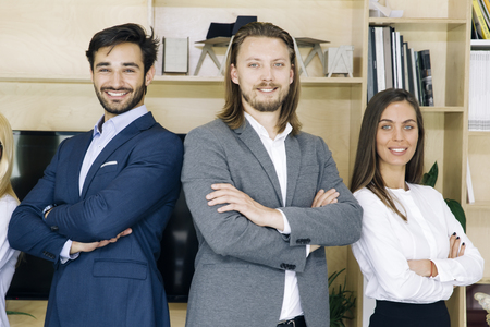 Portrait of friendly businesspeople in suits standing at officeの写真素材