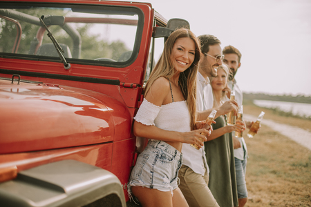 Young people drinking and having fun by car outdoor at hot summer dayの写真素材