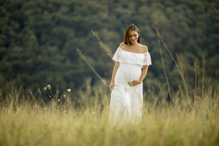 Young pregnant woman relaxing outside in nature at summer dayの写真素材
