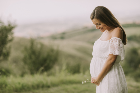 Young pregnant woman relaxing outside in nature at summer dayの写真素材
