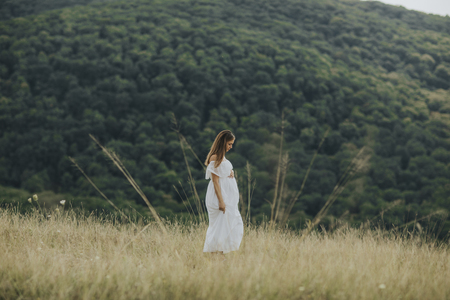 Young pregnant woman relaxing outside in nature at summer dayの写真素材