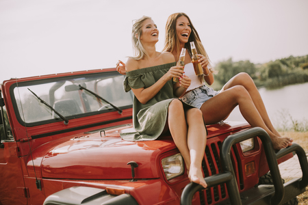 Attractive young women having fun on a convertible car by riverの写真素材