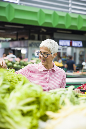 Portrait of senior woman buying fresh organic vegetable on marketの写真素材