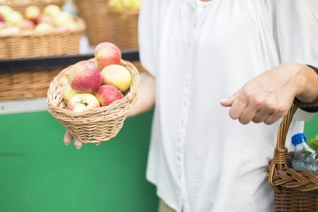 Portrait of senior woman buying  apples in punnet on marketの写真素材