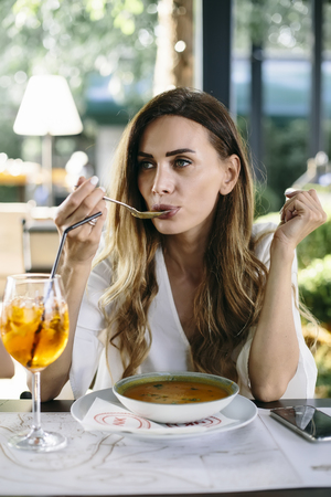 Young  attractive woman eating soup in restaurantの写真素材