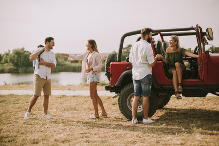 Young people having fun by cabriiolet car and  riverの写真素材