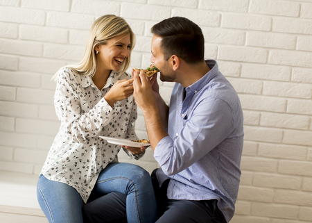 Loving couple relaxing at home and eating tasteful pizzaの写真素材