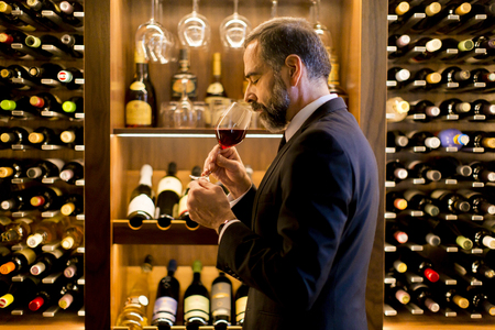 Handsome elegant businessman drinking red wine in barの写真素材