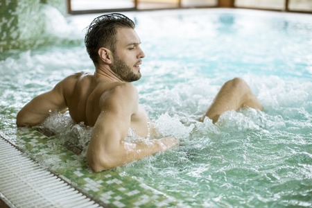 Handsome young man relaxing in hot tub in spaの写真素材