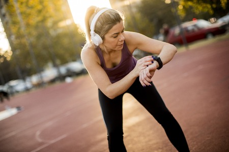 Sportwoman checking pulse on fitness smart watch device at outdoorの写真素材