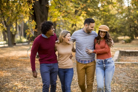 Multiracial young people walking in the autumn park and having funの写真素材