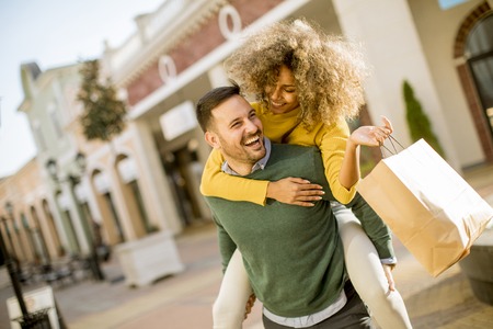 Portrait of  young man holds young woman on his back , have fun and go to shoppingの写真素材