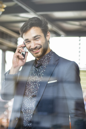 Happy young man using his smart phone at modern officeの写真素材