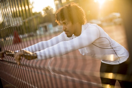 Handsome young man stretching during outdoor training
