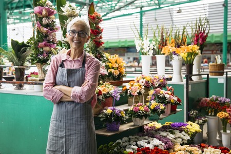Portrait of charrming senior woman sales flowers on local marketの写真素材