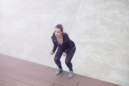 Fitness woman jumping outdoor in urban enviroment by day