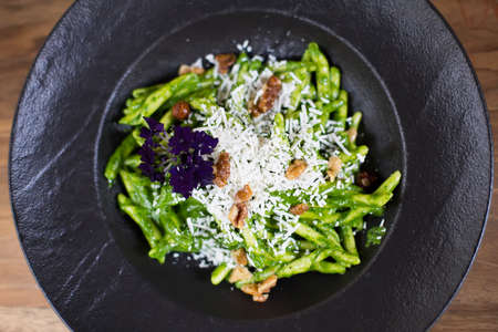 Pasta with spinach pesto and goat cheese on the plate at the tableの写真素材