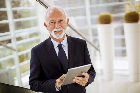 Portrait of senior businessman with digital  tablet in modern office officeの写真素材