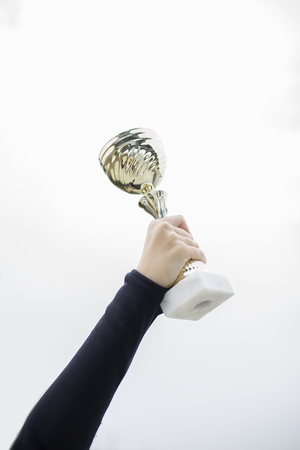 Successful young woman holds a trophy outdoorの写真素材