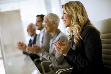 Satisfied proud business team clapping hands while sitting in row at officeの写真素材