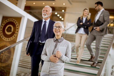 Group of businessmen and businesswomen walking and taking stairs in an office buildingの写真素材