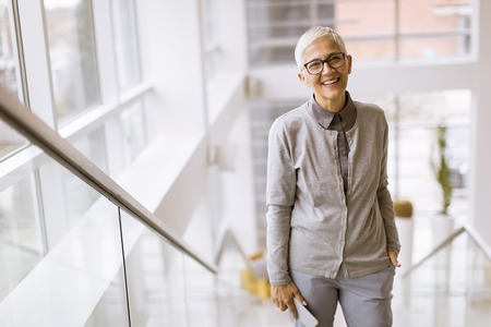 Portrait of senior businesswoman standing on the stairs in office