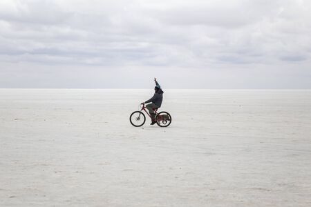 SALAR DE UYUNI, BOLIVIA - JANUARY 13, 2018: Unidentified man on the bicycle with a dog at Salar de uyuni in Bolivia. It is the worlds largest salt flat.のeditorial素材