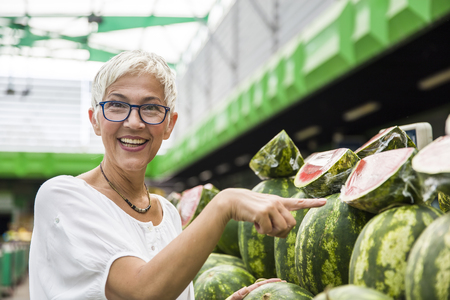 Portrait of senior woman buying watermelon on marketの写真素材