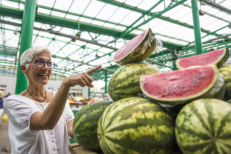 Portrait of senior woman buying watermelon on marketの写真素材