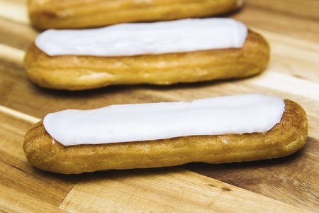 Eclair crispy creamy cake with white chocolate isolated on wooden background
